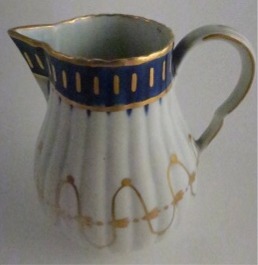 Worcester Pear Shaped Milk Jug and Cover, moulded fluted body, shallow domed cover with flower finial. Decorated in underglaze cobalt blue and rich gilding, c1775