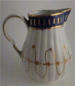 Worcester Pear Shaped Milk Jug and Cover, moulded fluted body, shallow domed cover with flower finial. Decorated in underglaze cobalt blue and rich gilding, c1775