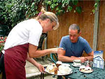 The waitress brings a tray containing the cakes available.